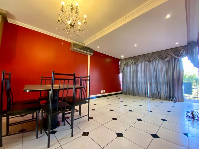 Spacious living area featuring tiled flooring, recessed downlighting, and a split-system air conditioner, with direct access to an outdoor balcony through sliding glass doors.