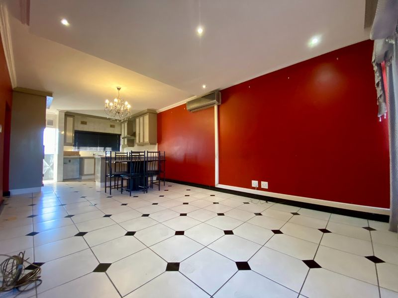 Open plan living and kitchen area featuring tiled flooring, recessed lighting, and a wall-mounted air conditioning unit.