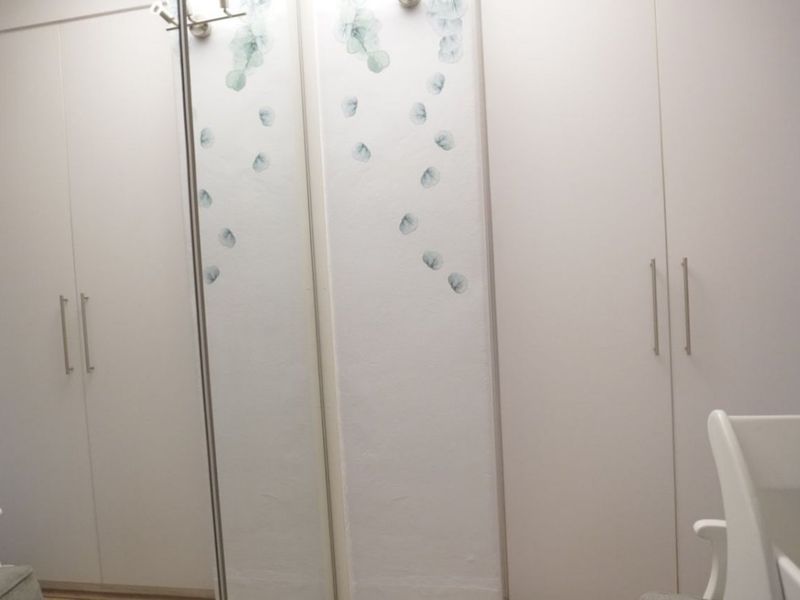 A bedroom featuring floor-to-ceiling built-in cupboards with integrated mirrored panels and modern handles.