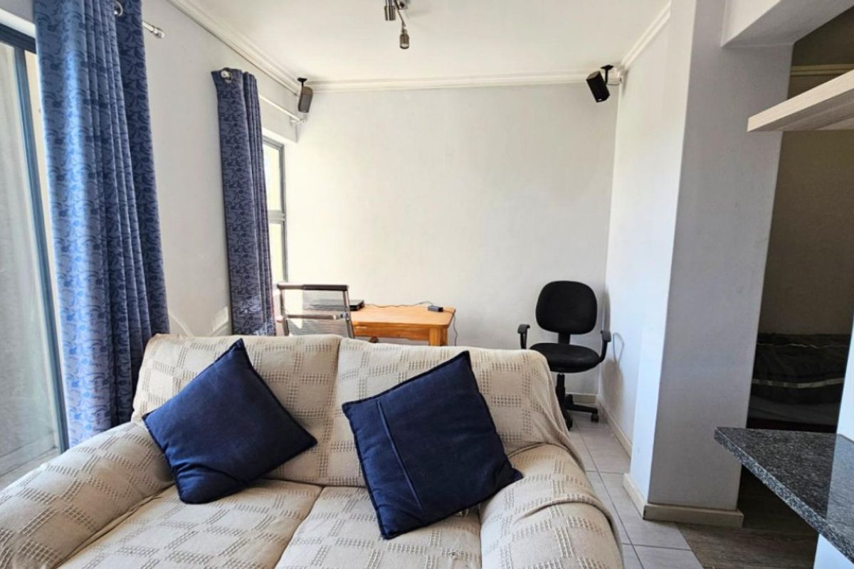 A living room area featuring tiled flooring, coving, and a sliding glass door providing natural light.