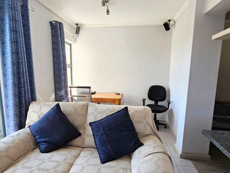 A living room area featuring tiled flooring, coving, and a sliding glass door providing natural light.