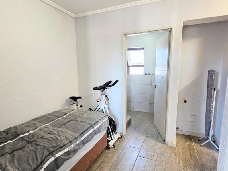 A bedroom featuring tiled flooring and an adjoining bathroom, providing a functional layout with neutral wall finishes.