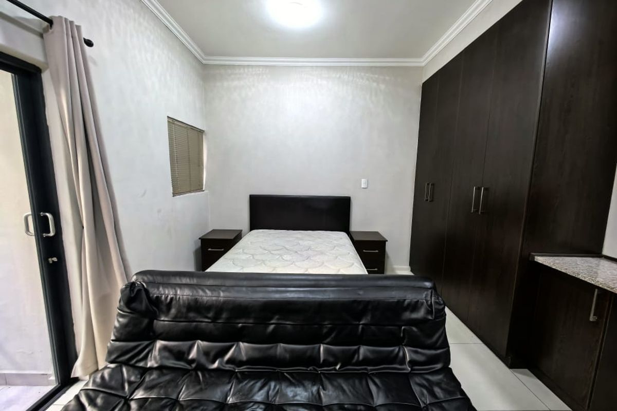 A bedroom featuring dark wood built-in cupboards, tiled flooring, and a sliding door providing access to an outdoor area.