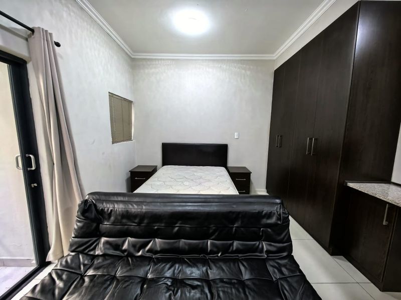 A bedroom featuring dark wood built-in cupboards, tiled flooring, and a sliding door providing access to an outdoor area.