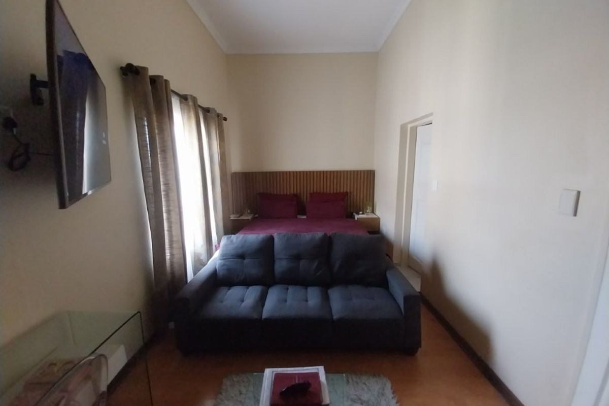 A bedroom featuring laminate flooring, a built-in headboard, and a high coved ceiling, providing a functional and compact living space.