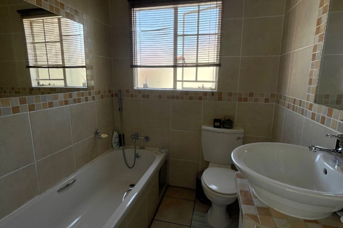 A functional bathroom featuring a bathtub, toilet, and vanity basin with tiled finishes throughout.