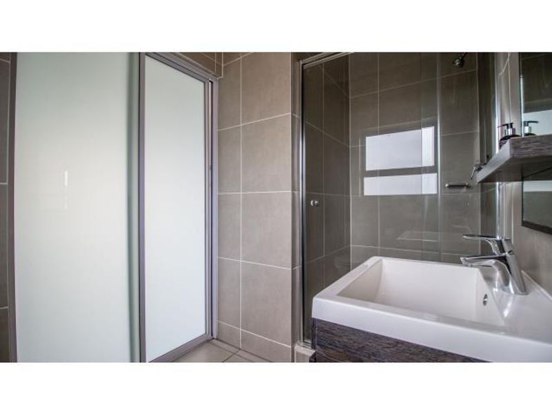 Modern bathroom featuring a glass-enclosed shower, contemporary vanity basin with mixer tap, and neutral wall tiling.