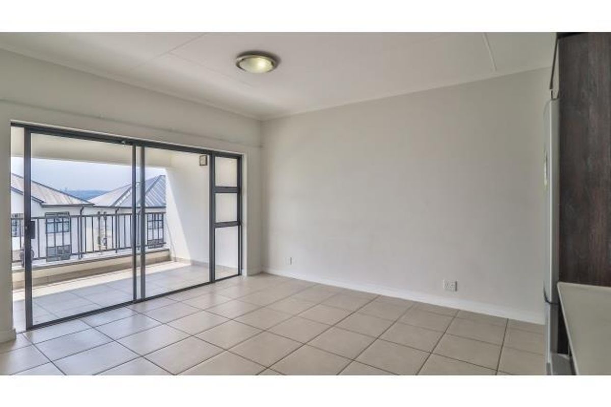 Bright and spacious living area featuring neutral tiled flooring and large sliding glass doors that open onto a private balcony.