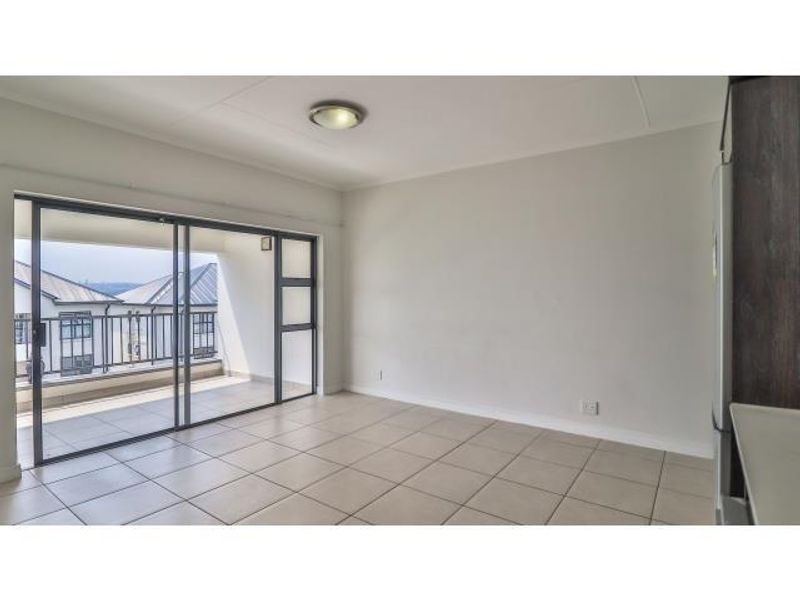 Bright and spacious living area featuring neutral tiled flooring and large sliding glass doors that open onto a private balcony.