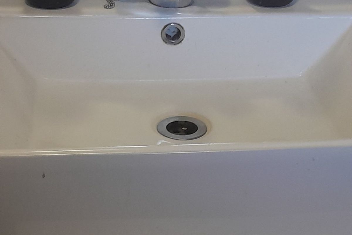 A close-up view of a bathroom vanity basin featuring a chrome mixer tap and integrated overflow drain.