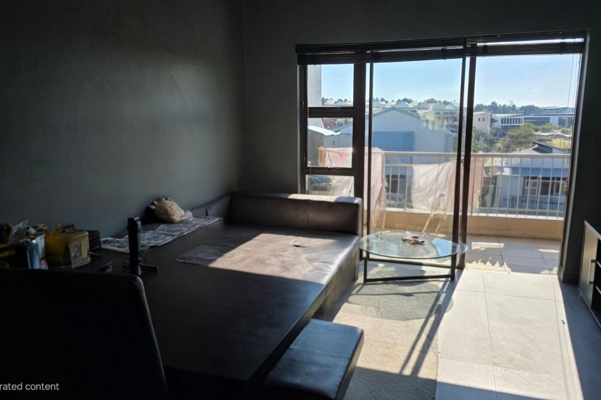 A living room area featuring tiled flooring and large sliding glass doors that provide access to an outdoor balcony.