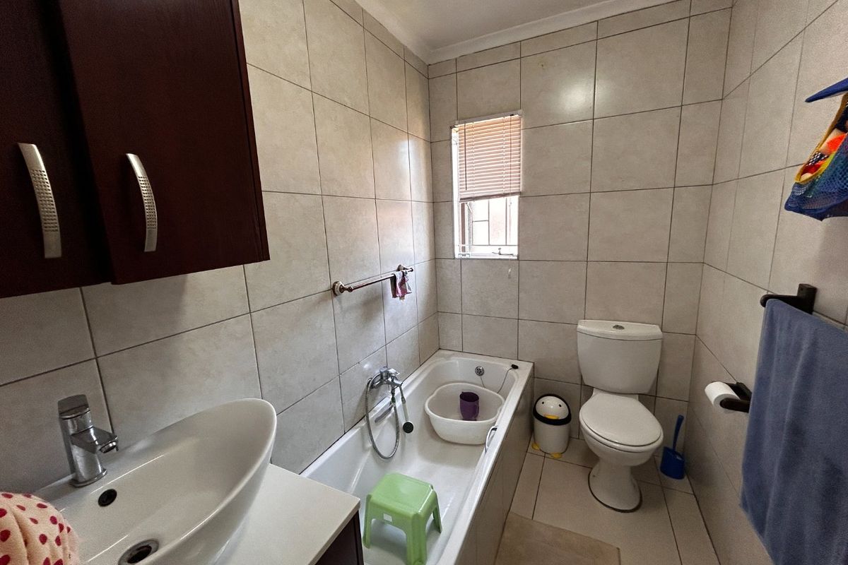 A functional bathroom featuring a bathtub, toilet, and a modern vessel sink set on a vanity cabinet with tiled finishes throughout.