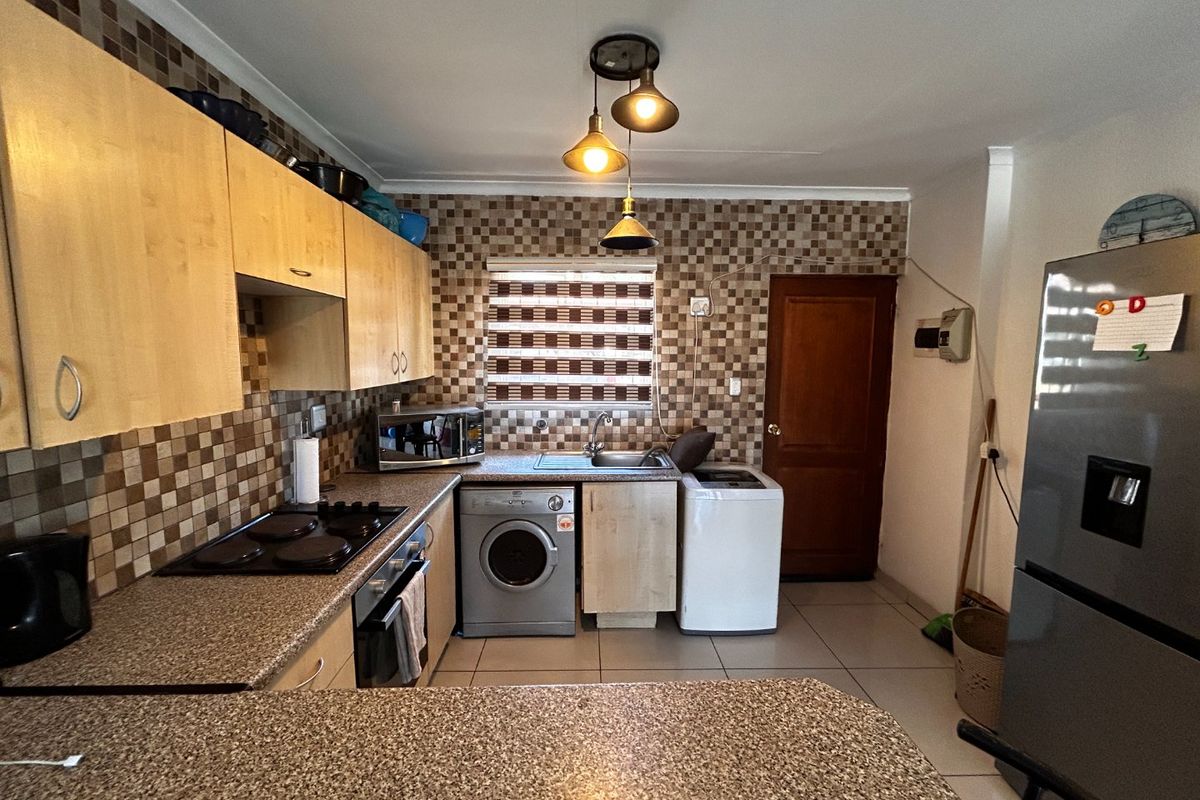 A functional kitchen featuring mosaic tile backsplashes, laminate countertops, built-in cabinetry, and integrated appliances including an oven and hob.
