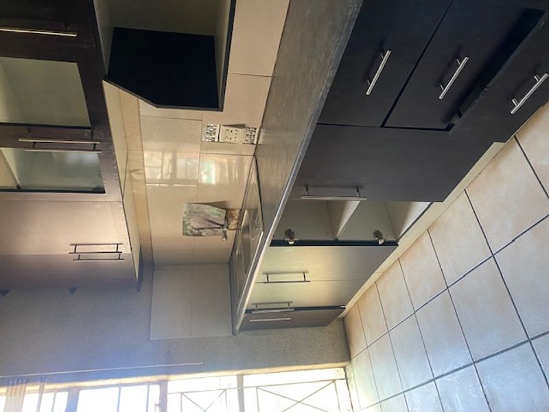 A functional kitchen featuring dark cabinetry, laminate countertops, and a stainless steel sink, requiring some maintenance and cosmetic updates.