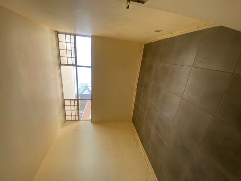 An empty bedroom featuring tiled flooring and multi-pane windows, requiring cosmetic attention to the wall surfaces.
