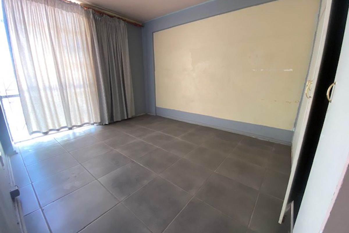 An empty bedroom featuring tiled flooring, a built-in cupboard, and a sliding door leading to an outdoor area.
