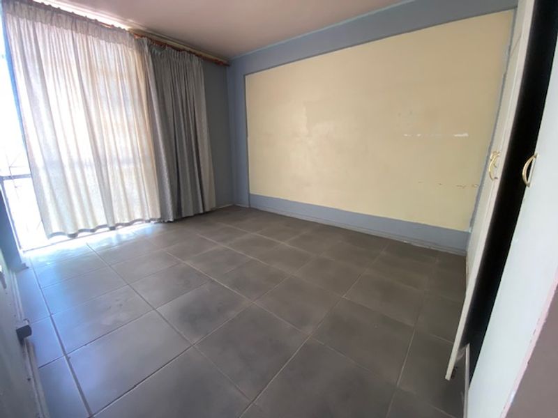 An empty bedroom featuring tiled flooring, a built-in cupboard, and a sliding door leading to an outdoor area.