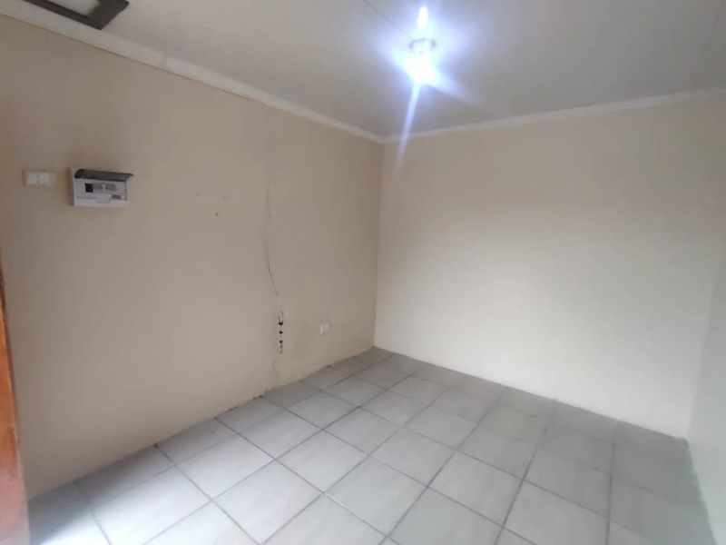 An empty bedroom featuring tiled flooring and a visible vertical wall crack, providing a blank canvas for renovation.