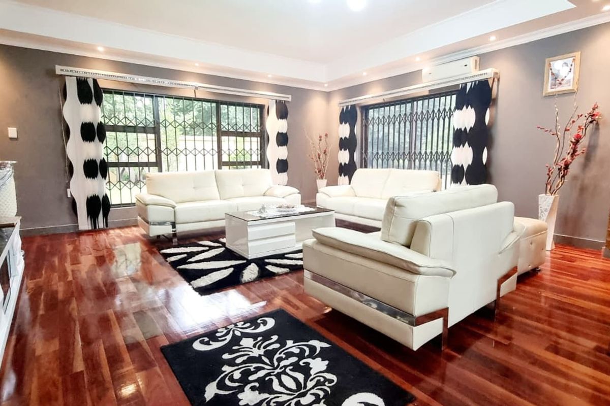 Spacious living room featuring polished hardwood flooring, recessed ceiling lighting, a split-system air conditioner, and a decorative stone feature wall.