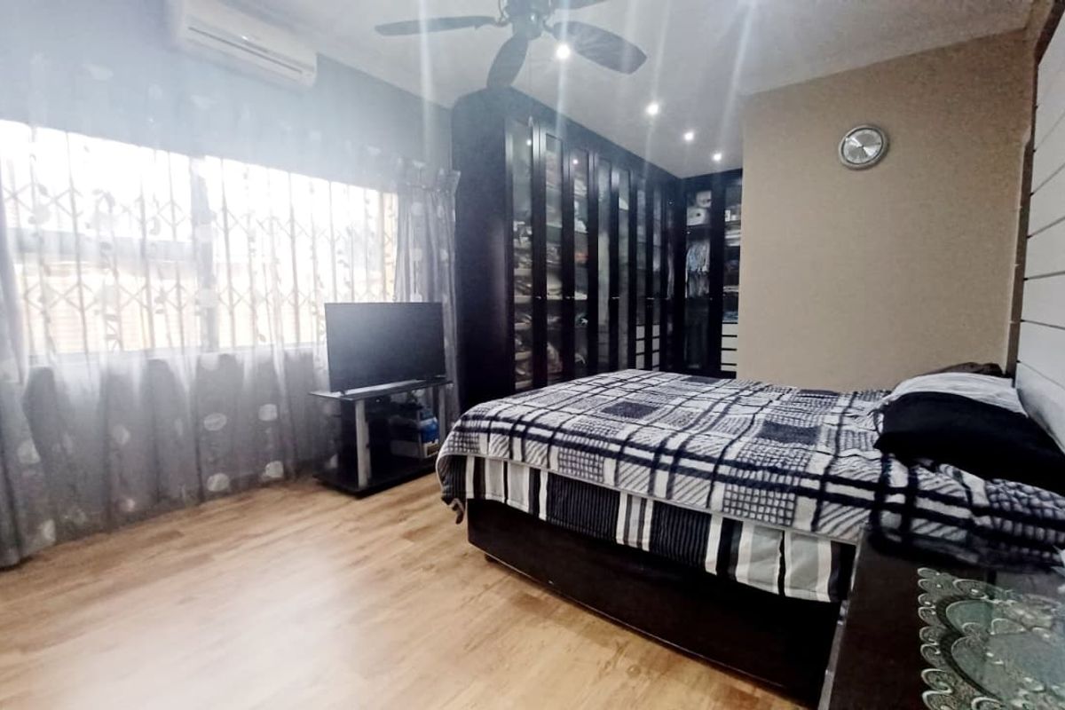 A bedroom featuring laminate flooring, built-in cupboards, a ceiling fan, and an air conditioning unit.