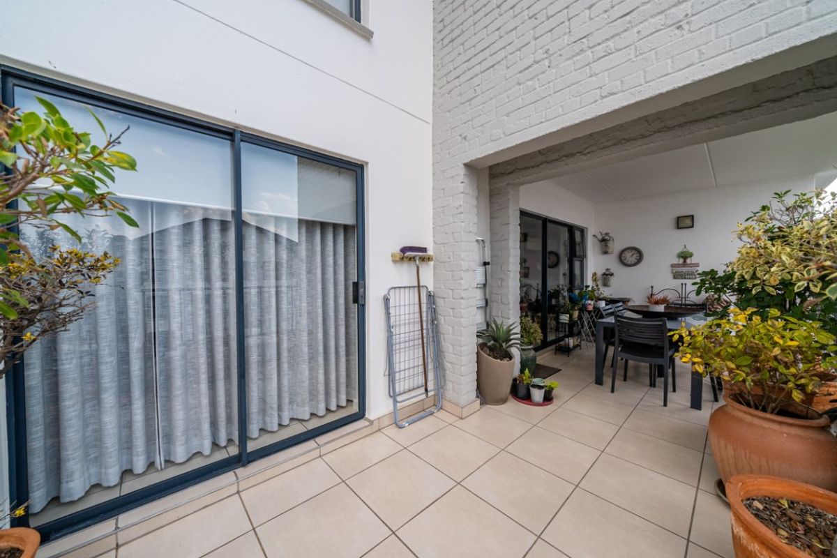 A covered patio area featuring tiled flooring and sliding glass doors, providing a seamless transition between indoor and outdoor living spaces.