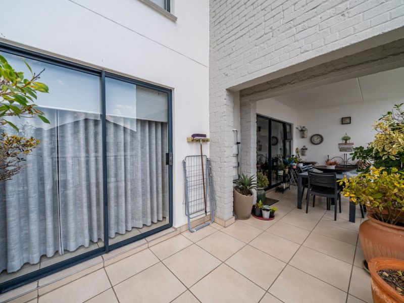 A covered patio area featuring tiled flooring and sliding glass doors, providing a seamless transition between indoor and outdoor living spaces.