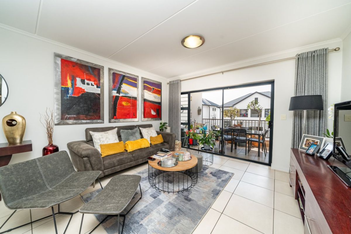 A bright living room featuring tiled flooring and a large sliding glass door that provides access to an outdoor balcony area.