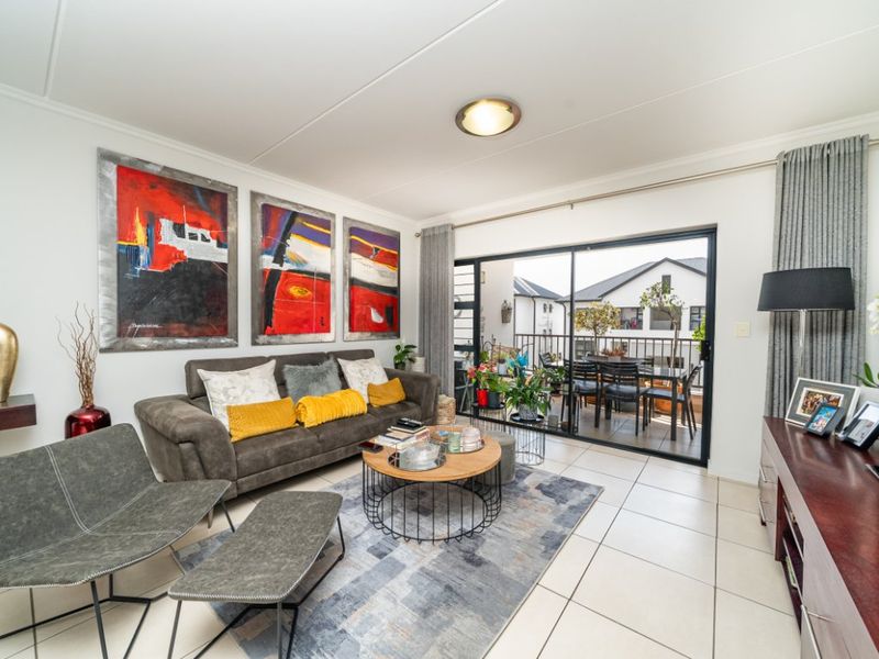 A bright living room featuring tiled flooring and a large sliding glass door that provides access to an outdoor balcony area.