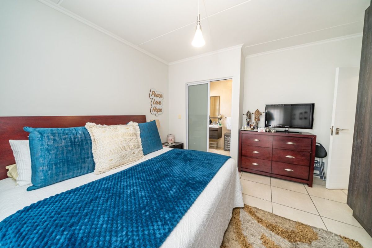 A well-maintained bedroom featuring tiled flooring, a built-in cupboard, and an en-suite bathroom accessible via a sliding door.