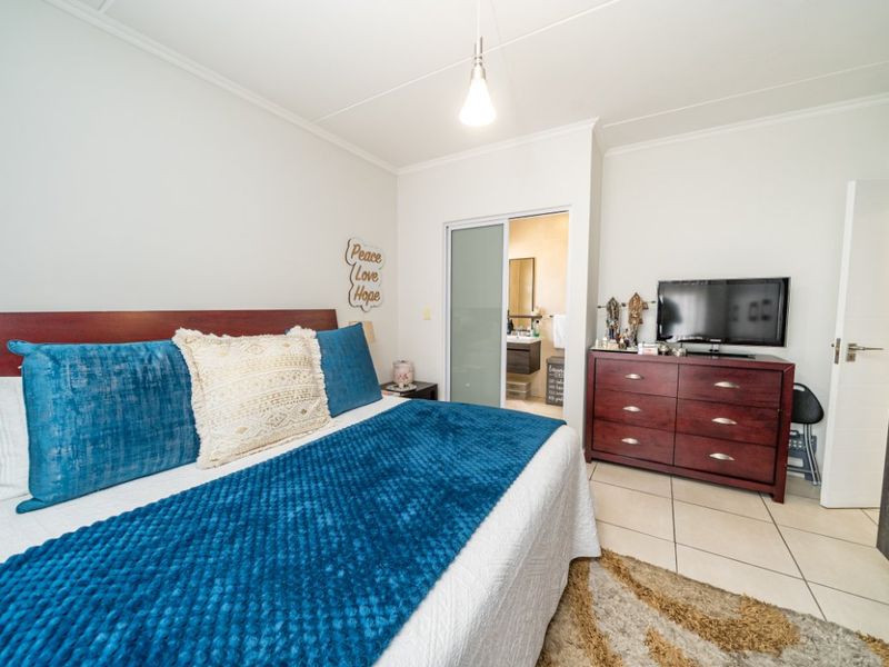 A well-maintained bedroom featuring tiled flooring, a built-in cupboard, and an en-suite bathroom accessible via a sliding door.