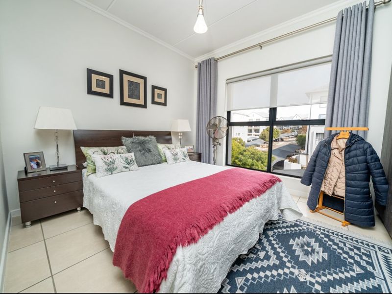 A well-lit bedroom featuring tiled flooring, a large window with views, and built-in wardrobe storage.