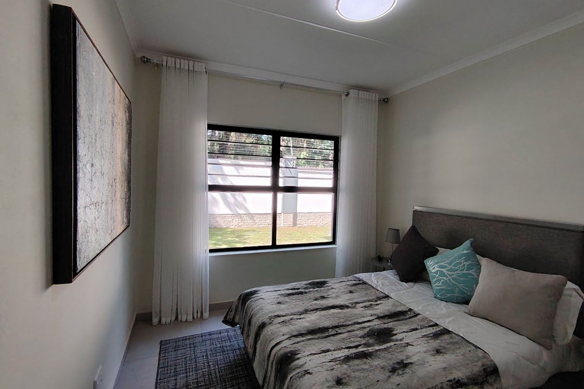 A well-maintained bedroom featuring tiled flooring, a central ceiling light, and a window with security bars overlooking the exterior.