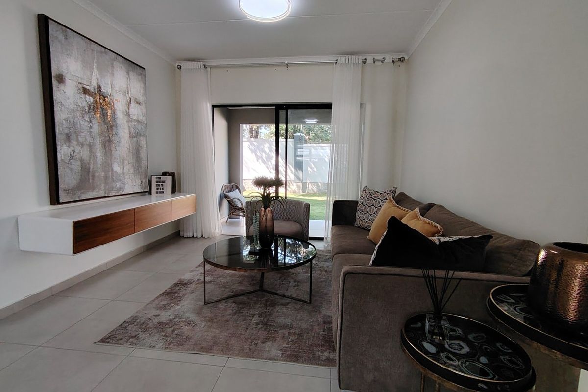A well-maintained living room featuring tiled flooring, a modern floating media console, and a sliding glass door leading to an outdoor patio area.