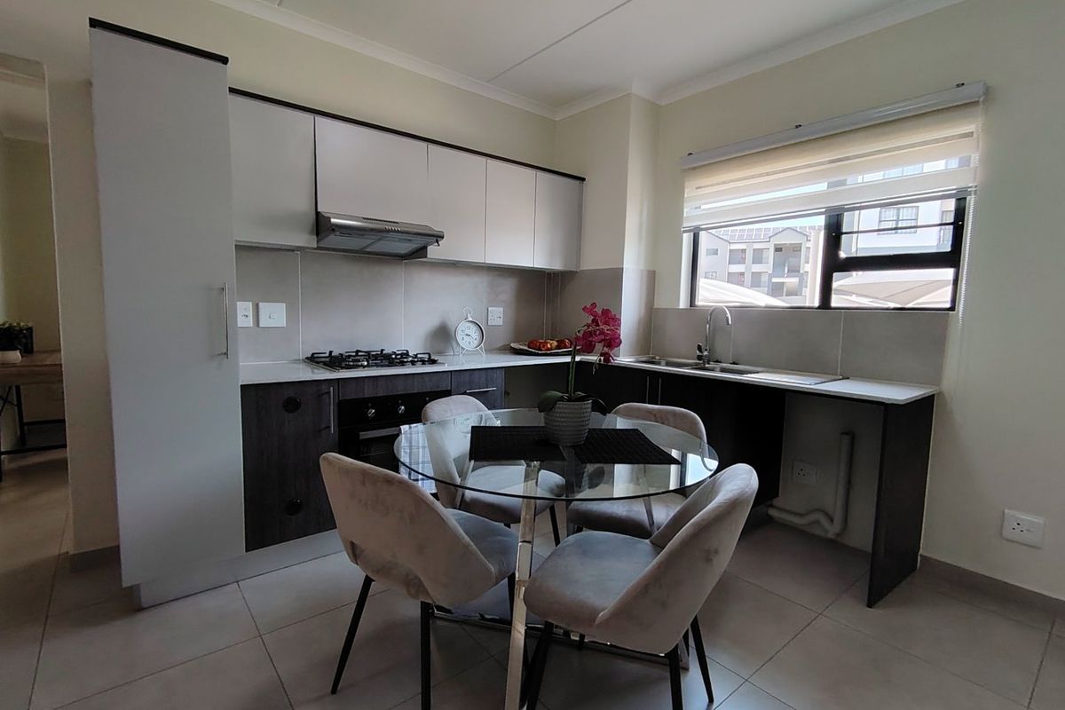 Modern kitchen featuring sleek two-tone cabinetry, gas hob, integrated oven, extractor fan, and tiled finishes with ample natural light.