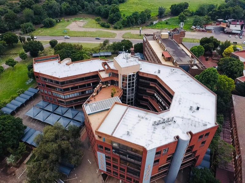 Aerial view of a multi-story commercial office building featuring a central courtyard, brick exterior, and extensive covered parking facilities.