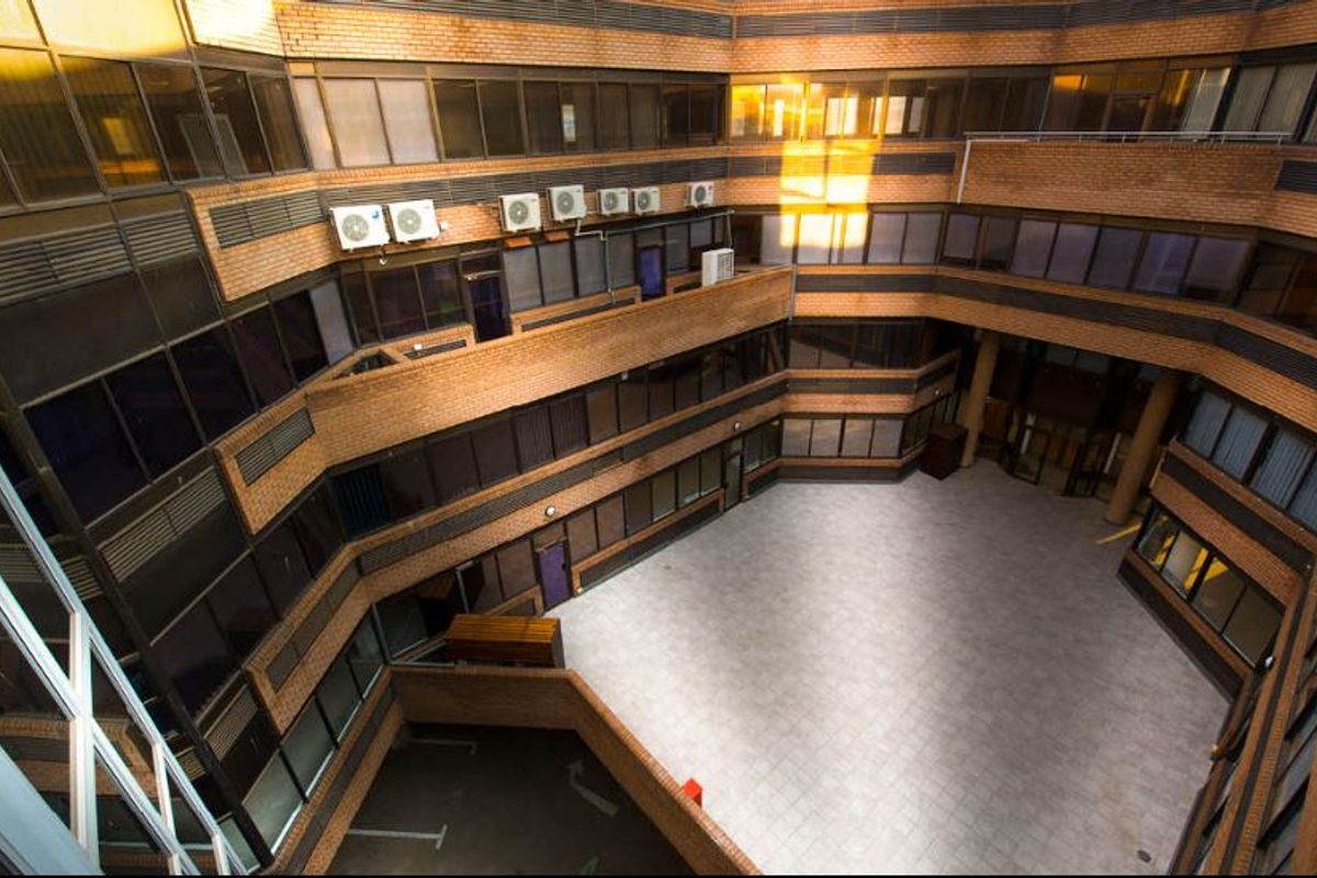 An elevated view of a commercial building's central courtyard featuring brick facade, tiled flooring, and multiple levels of office windows.