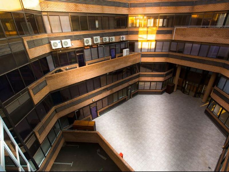 An elevated view of a commercial building's central courtyard featuring brick facade, tiled flooring, and multiple levels of office windows.