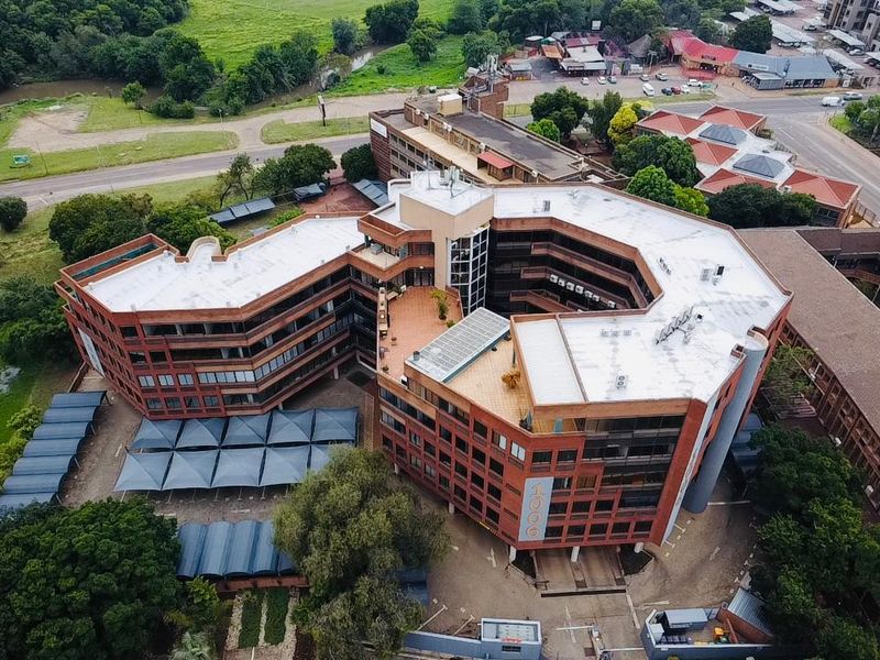 Aerial view of a multi-story commercial office complex featuring a brick facade, central courtyard, and extensive covered parking facilities.