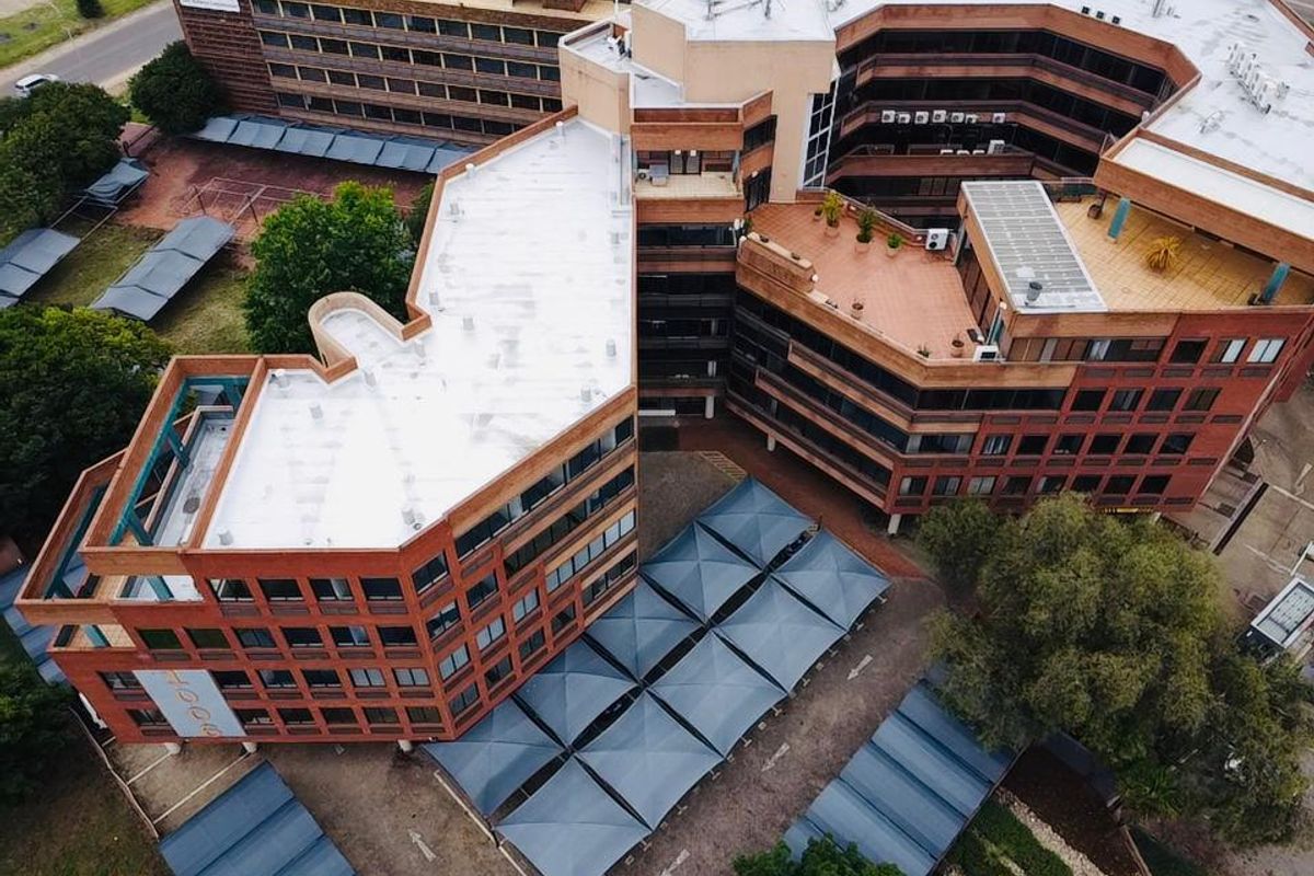 Aerial view of a multi-story commercial office complex featuring brick architecture, flat roofing, and extensive covered parking facilities.
