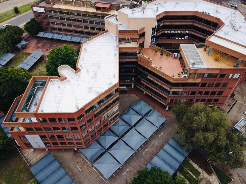 Aerial view of a multi-story commercial office complex featuring brick architecture, flat roofing, and extensive covered parking facilities.