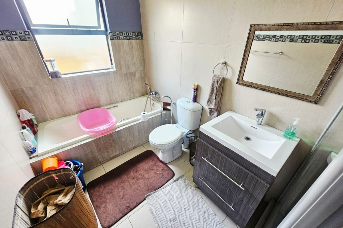 A functional bathroom featuring a built-in bathtub, a modern vanity cabinet with basin, and tiled finishes throughout.