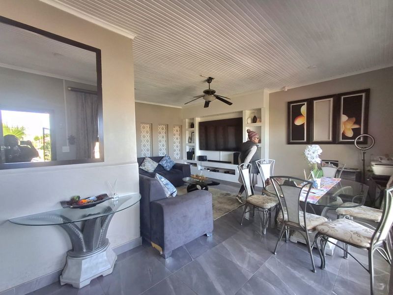 Open-plan living and dining area featuring tiled flooring, a tongue and groove ceiling, and a built-in media unit.