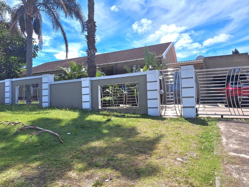 Front view of the property featuring a secure perimeter wall with stainless steel gates and a tiled roof structure.