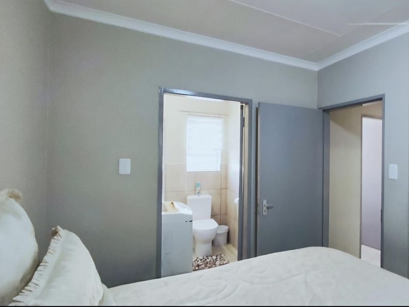 A bedroom featuring an en-suite bathroom with neutral wall finishes and coving detail.