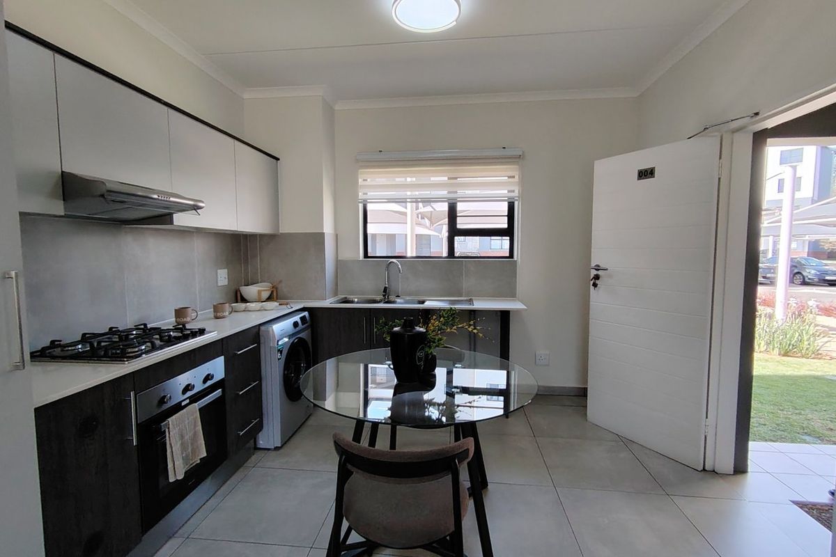 Modern kitchen featuring stone countertops, gas hob, built-in oven, extractor fan, and tiled flooring with direct access to the exterior.