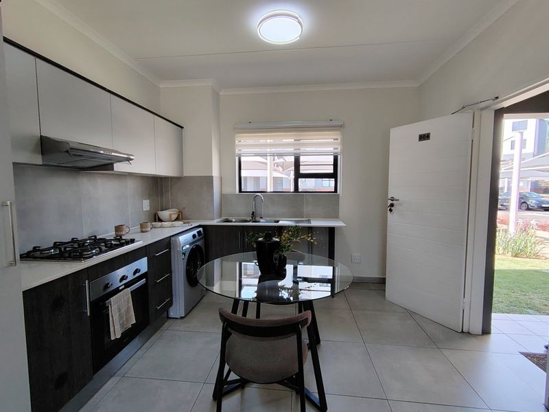 Modern kitchen featuring stone countertops, gas hob, built-in oven, extractor fan, and tiled flooring with direct access to the exterior.