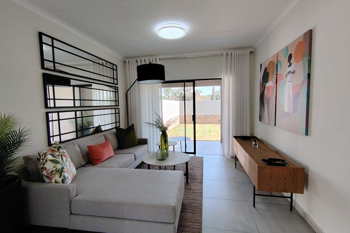 A bright and modern living room featuring large format floor tiles and a sliding glass door providing direct access to the rear garden area.
