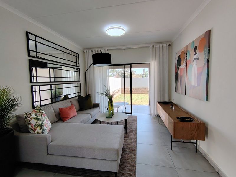 A bright and modern living room featuring large format floor tiles and a sliding glass door providing direct access to the rear garden area.