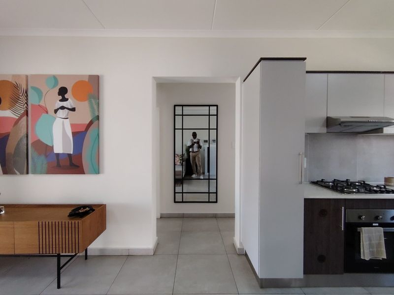 Modern open-plan kitchen area featuring sleek cabinetry, integrated gas hob, oven, extractor fan, and neutral tiled flooring throughout.