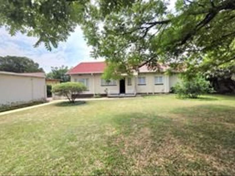 Front view of a single-story house featuring a pitched roof, a spacious front lawn, and a detached garage.